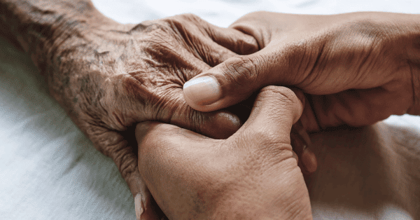 one person's hands holding the hand of an elderly person