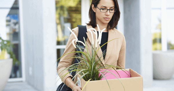 a woman carrying a box of files and plants